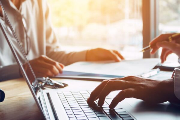 Workers compensation lawyer consulting with a client, showing hands typing on a laptop and reviewing legal documents, emphasizing personalized legal guidance for workplace injury claims.